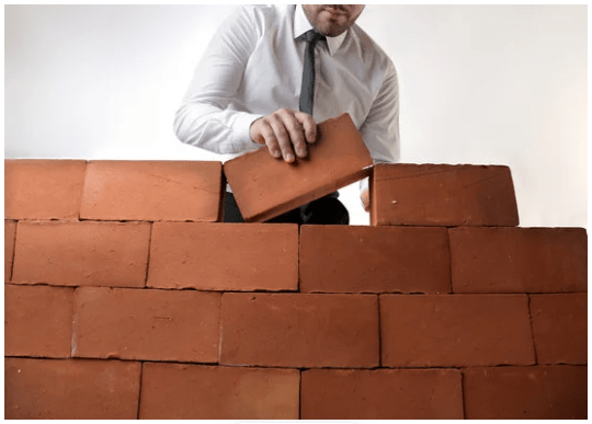 Un hombre con camisa y corbata construyendo un muro.