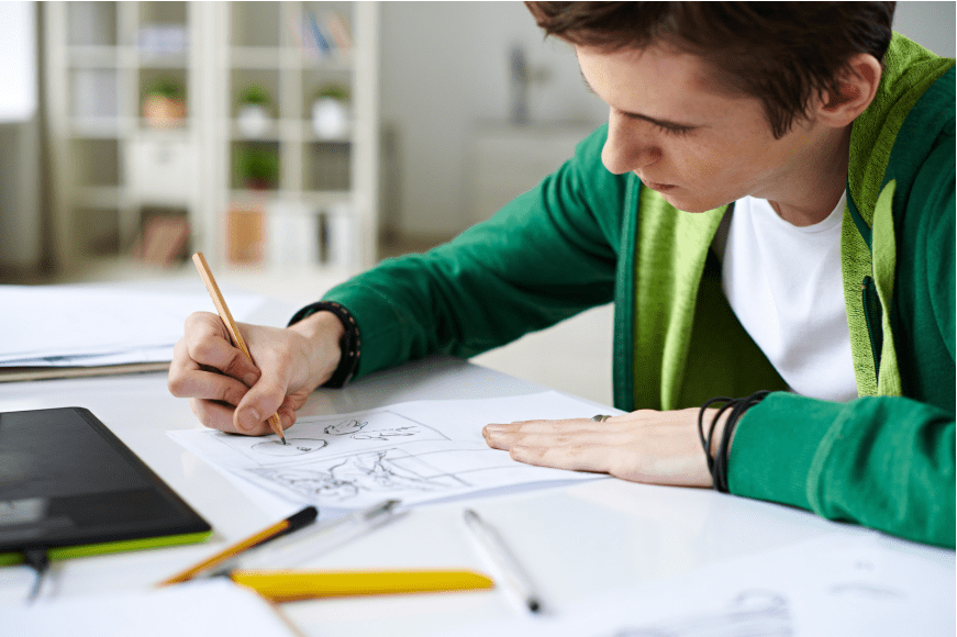 Un chico dibujando un cómic con un lápiz.