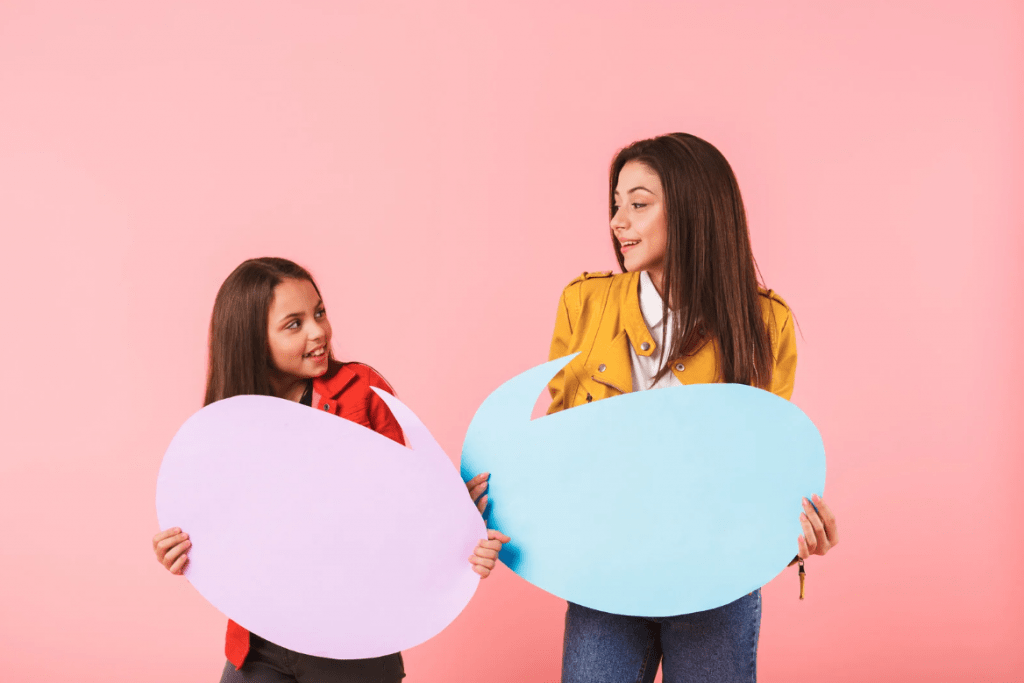 Dos chicas sujetando un bocadillo de texto de papel, en blanco.