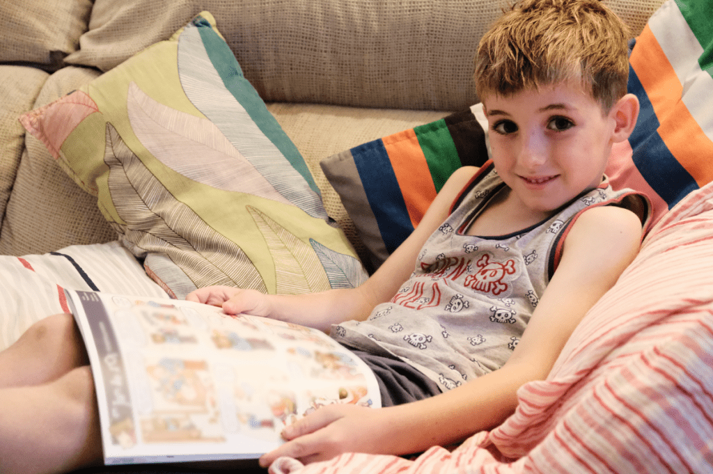 Un chico tumbado en el sofá, sujetando un cómic.
