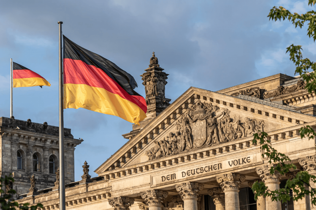 Un Edificio de fachada antigua con la bandera de Alemania alzada frente a él.