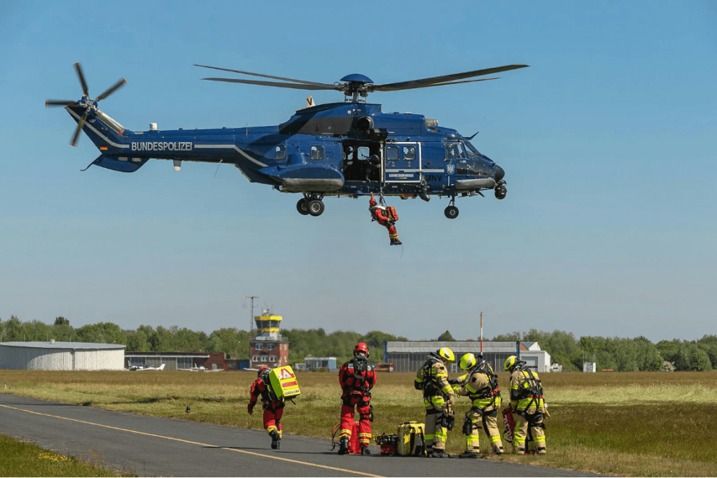Un grupo de trabajadores de emergencia bajo un helicóptero en pleno vuelo.