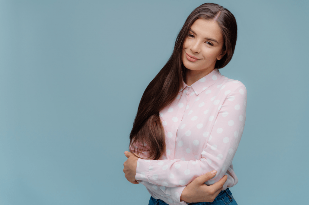Una joven de pelo liso y camisa rosa pálido.