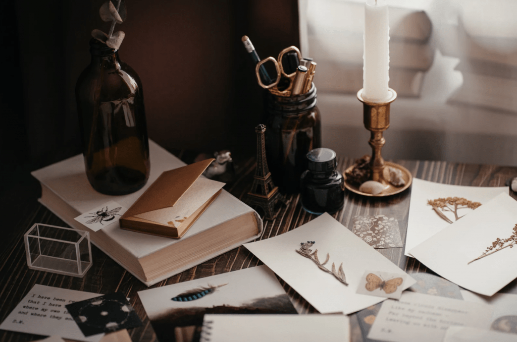 Una mesa con decoración antigua: velas, hojas prensadas, y ambiente melancólico.