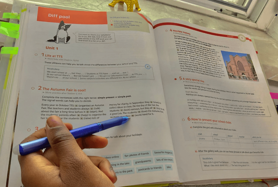 Una mano sujetando un bolígrafo sobre un libro de texto.