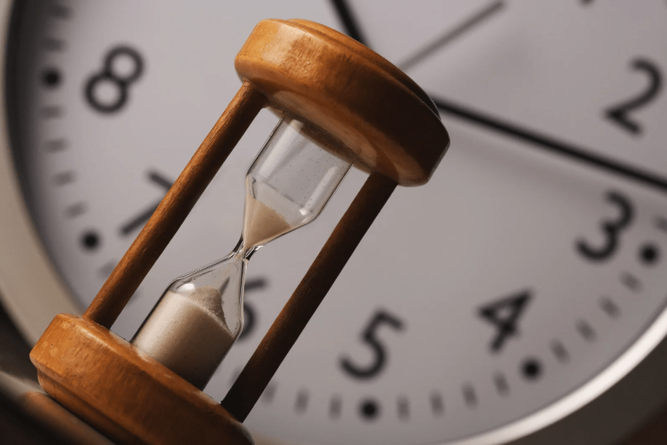 Un reloj de arena frente a un reloj analógico.