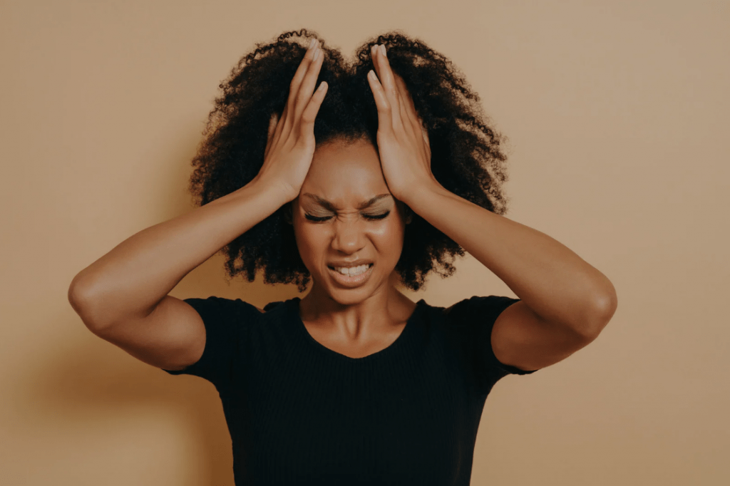 Una joven llevándose las manos a la cabeza en frustración.