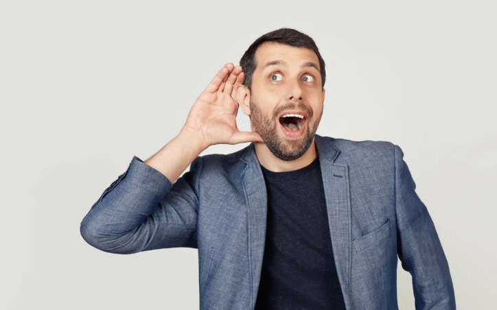 Un hombre con una mano agudizando el oído.