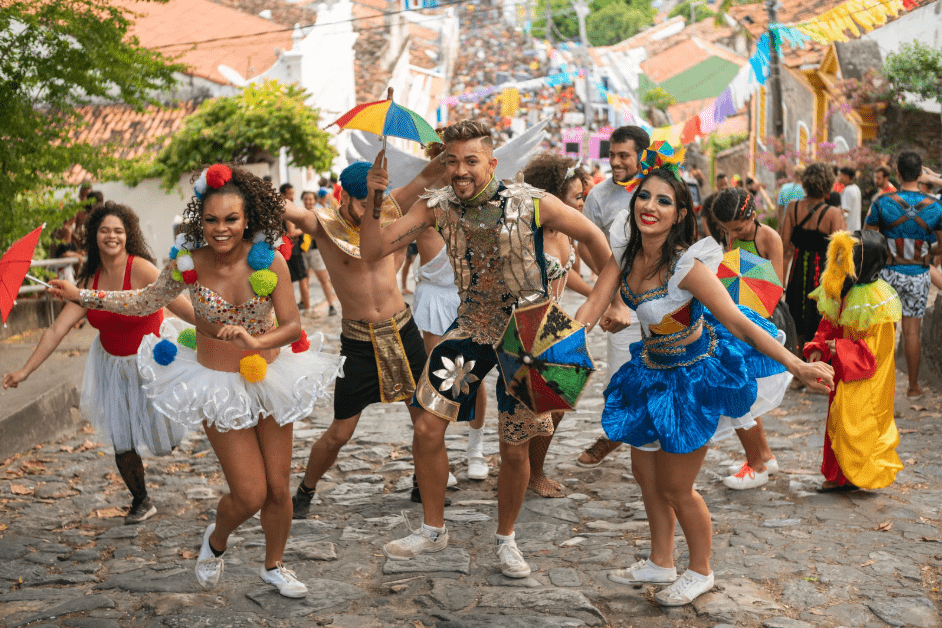 Un grupo de jóvenes con ropa colorida bailan en las calles.