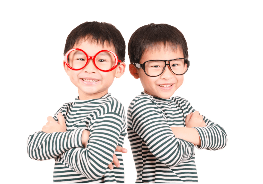 Dos niños vestidos muy parecidos, con gafas de distinta forma y color.