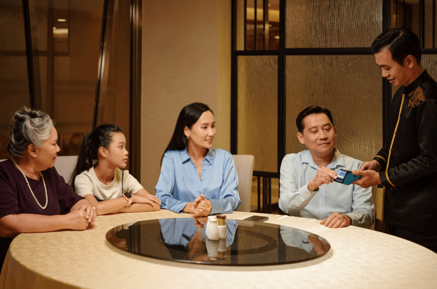 Un grupo de personas pagando una cuenta en un restaurante.