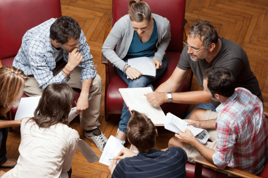 Un grupo de adultos conversando con unos papeles en la mano.