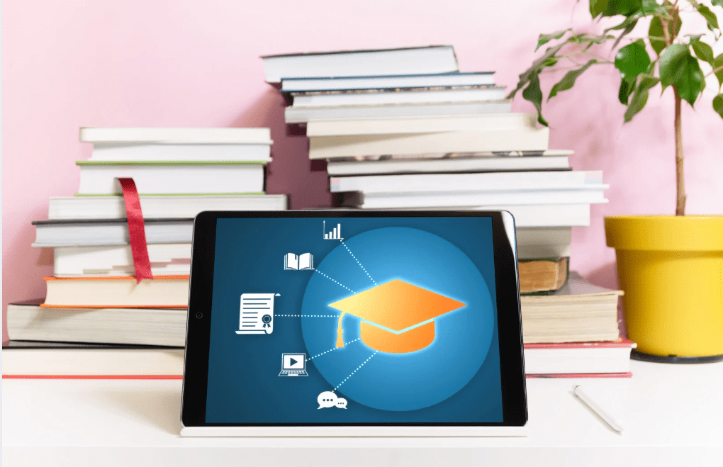 Una tablet frente a libros, mostrando iconos relacionados con la enseñanza.