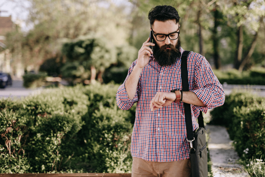 Un joven mirando el reloj mientras está al teléfono.
