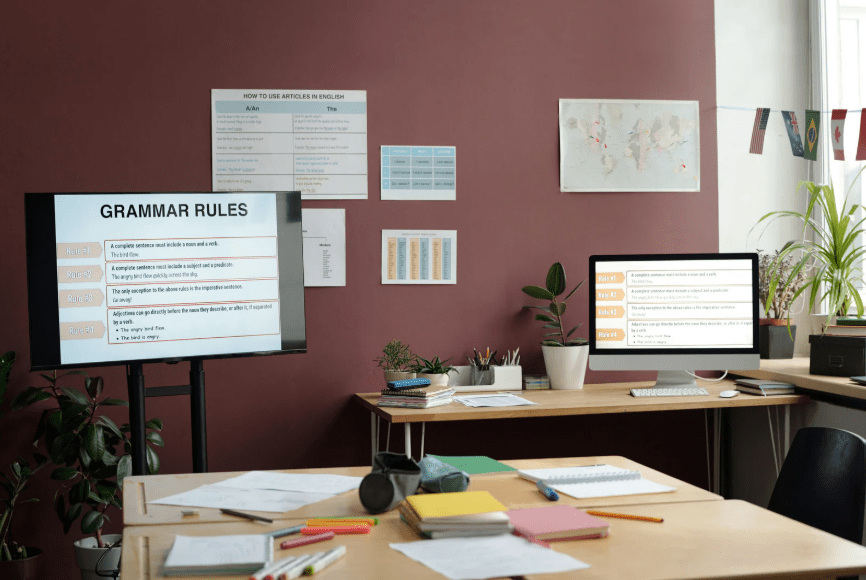 Una sala de profesores con una pantalla que reza "Grammar rules"