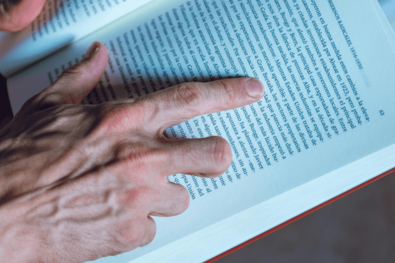 Unas manos adultas siguen las letras de un libro.