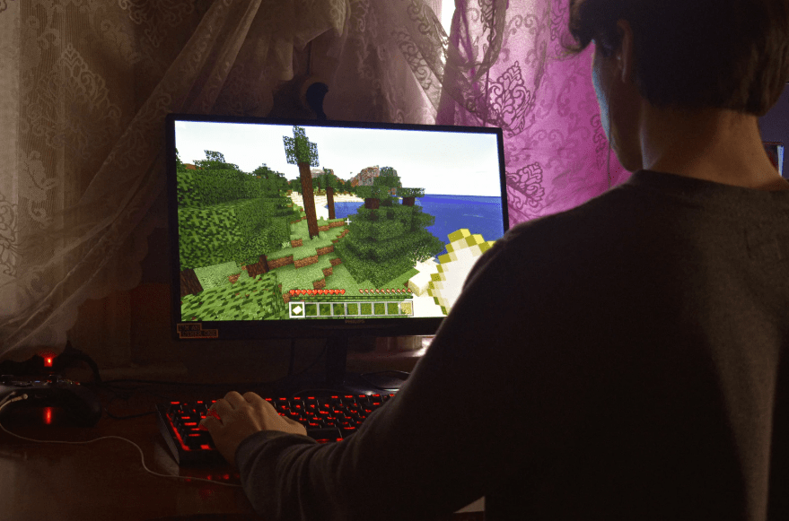 Un joven jugando al Minecraft en casi oscuridad.