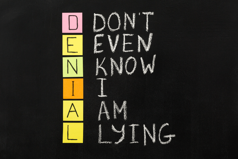 Un acrónimo en tiza que divide "DENIAL" EN "I Don't Even Know I Am Lying".