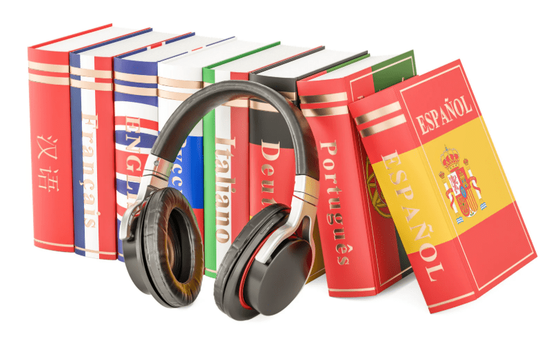 Una colección de libros de idiomas apoyan unos cascos.