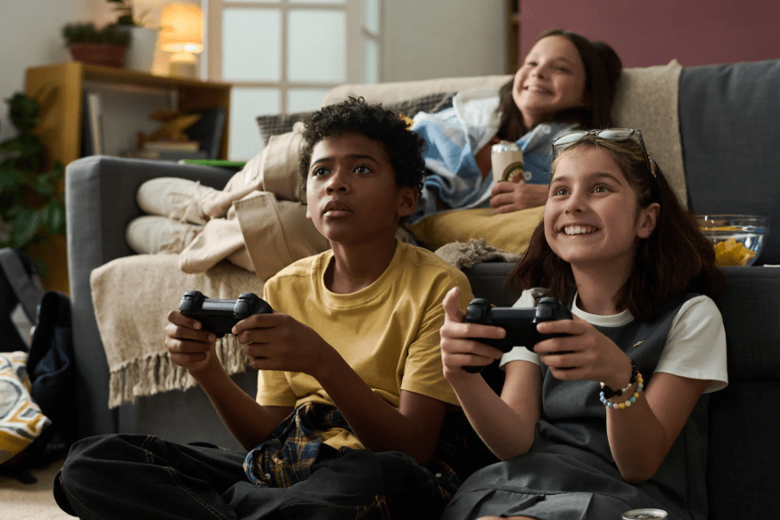 Tres niños, dos de ellos con un mando de consola cada uno.