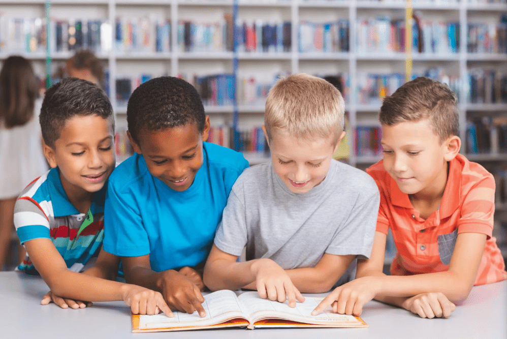 Cuatro niños comparten un libro.