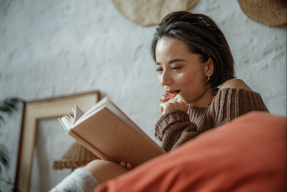 Una joven lee mientras come.