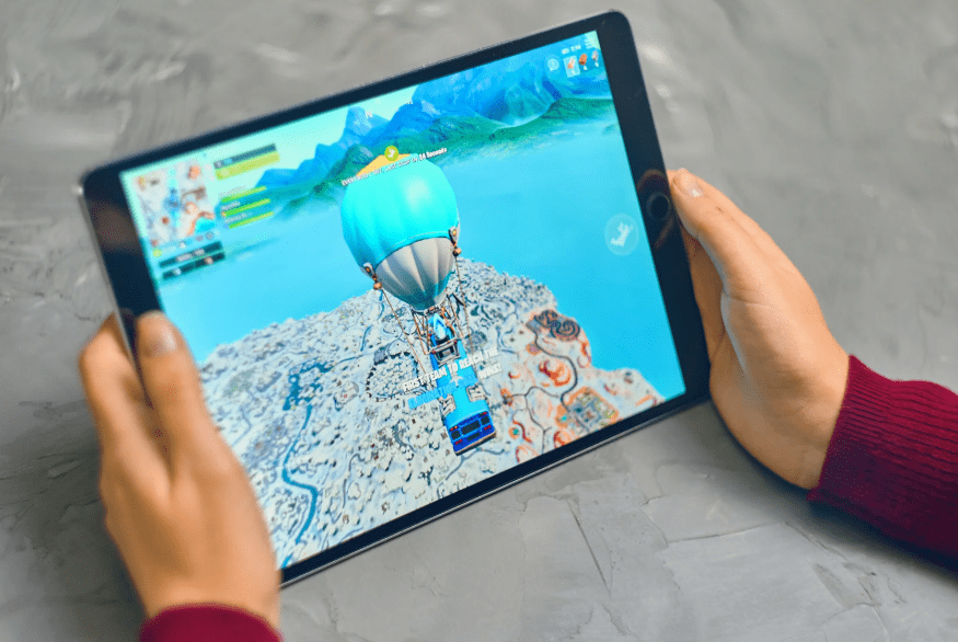 Unas manos sujetando una tablet en la que se juega al Fornite.