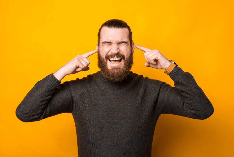 Un hombre tapándose los oídos con expresión tensa.