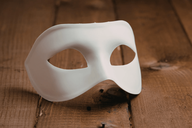 Una máscara blanca sobre madera.